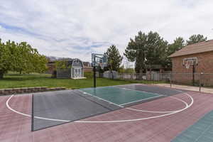 View of sport court with basketball hoop and a storage shed