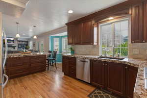 Kitchen featuring crown molding, light wood finished floors, a textured ceiling, pendant lighting, and tasteful backsplash