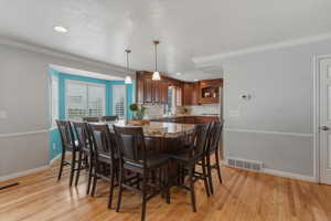 Dining area with light wood finished floors, ornamental molding, a textured ceiling, and recessed lighting