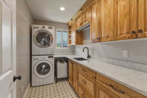 Laundry room with stacked washer / drying machine, recessed lighting, cabinet space, and light flooring