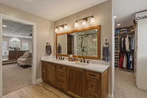 Bathroom featuring double vanity, a walk in closet, light carpet, recessed lighting, and a marble finish shower