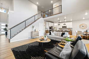 Living room featuring a high ceiling, light wood-style floors, and a chandelier