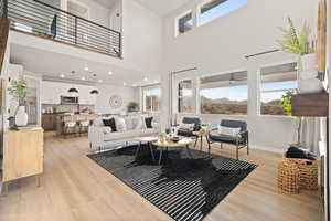 Living area featuring light wood-style floors, a high ceiling, and a mountain view
