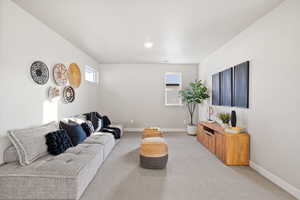 Living area with baseboards and light colored carpet