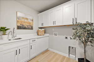 Laundry room featuring washer hookup, light wood-type flooring, cabinet space, and hookup for an electric dryer
