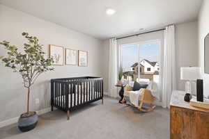 Carpeted bedroom with a crib and baseboards