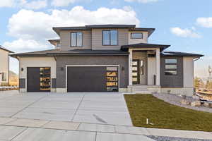 Prairie-style home with driveway, brick siding, a garage, and a front yard