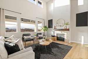 Living room with wood finished floors, a tiled fireplace, a high ceiling, and a mountain view