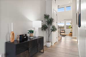 Corridor featuring light wood-style floors, plenty of natural light, and a high ceiling
