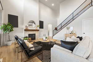 Living area featuring light wood-style flooring, a fireplace, a high ceiling, and recessed lighting