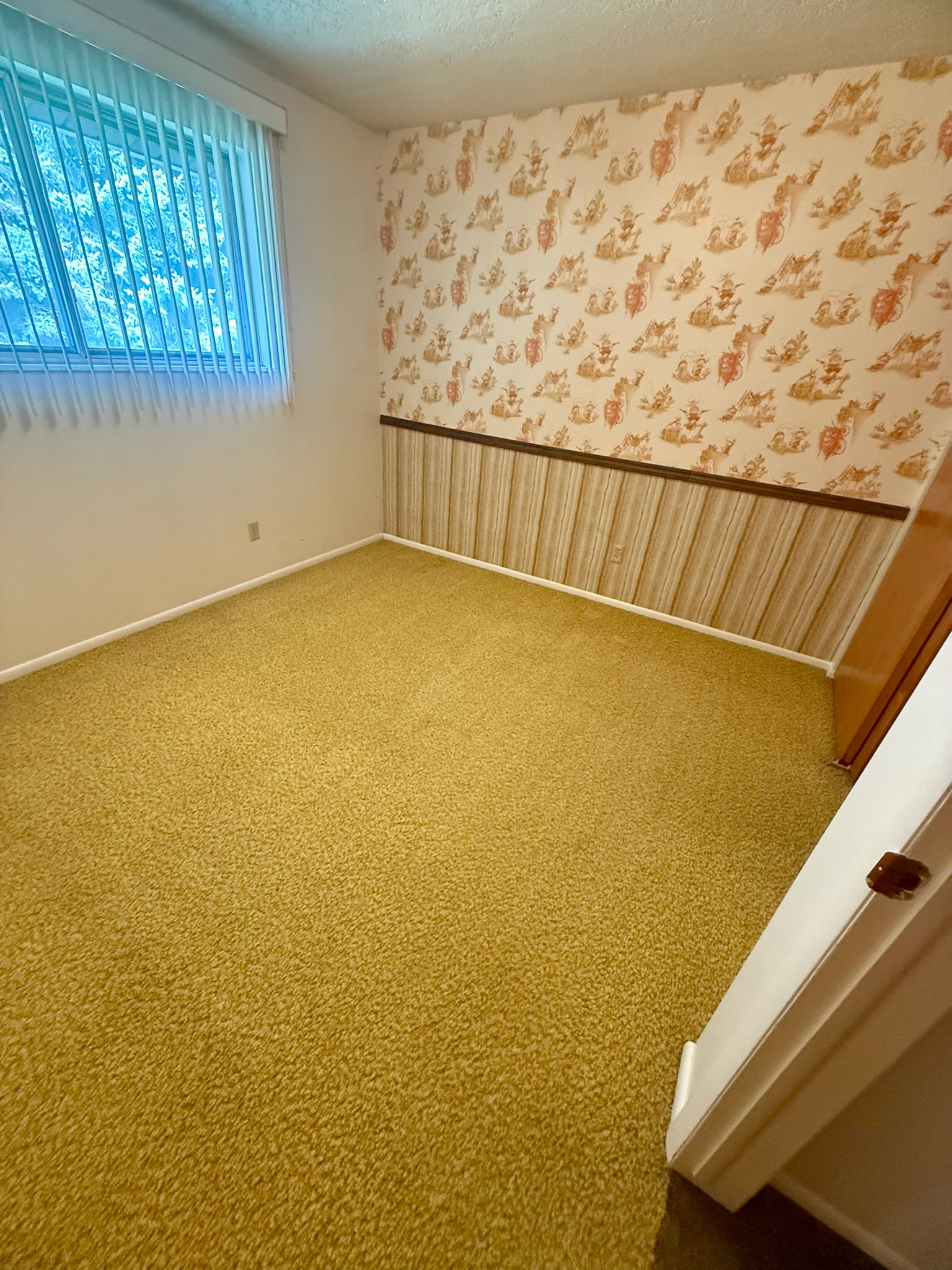 Unfurnished room with wallpapered walls and carpet