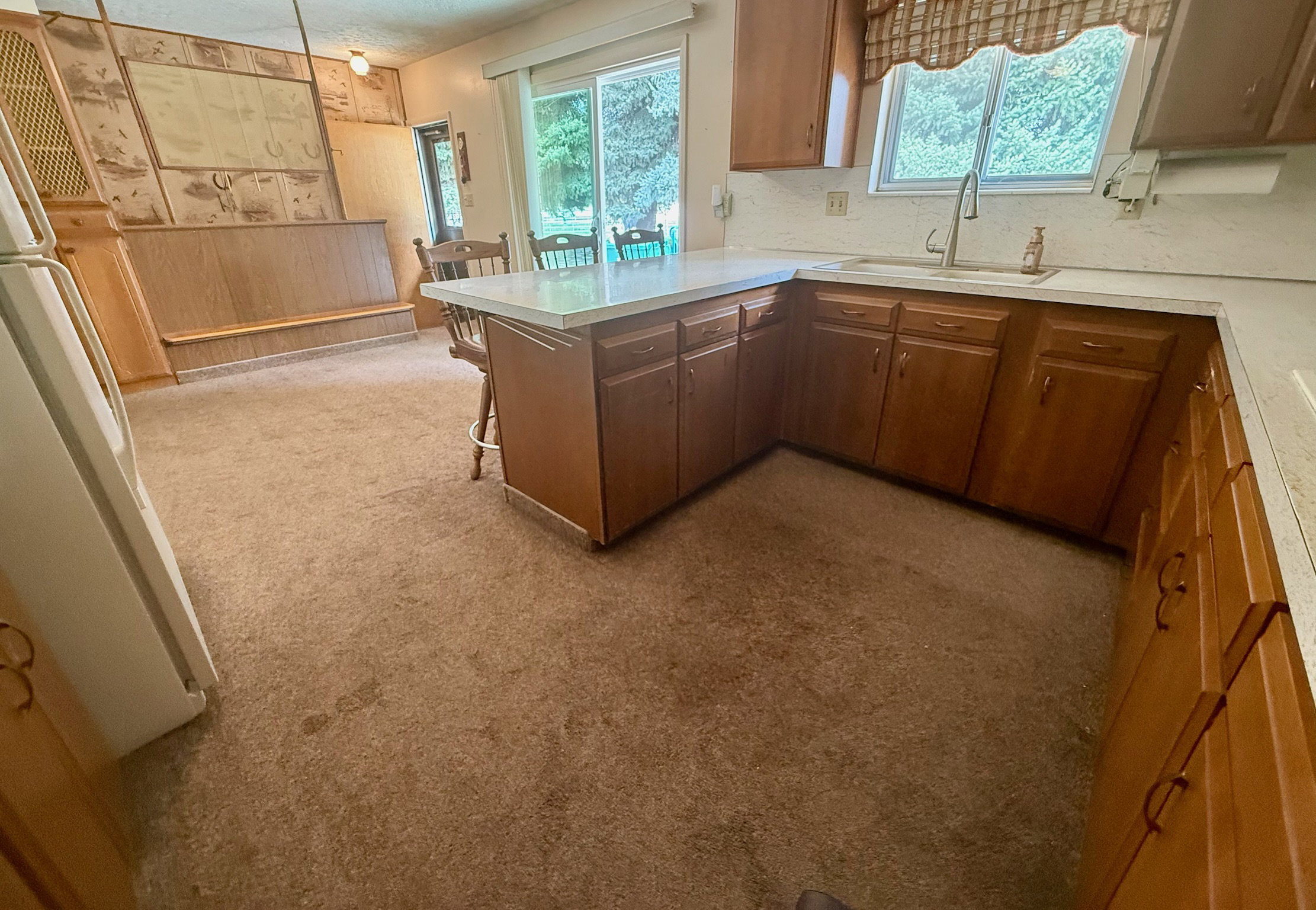 Kitchen featuring light countertops, a kitchen bar, a peninsula, freestanding refrigerator, and plenty of natural light