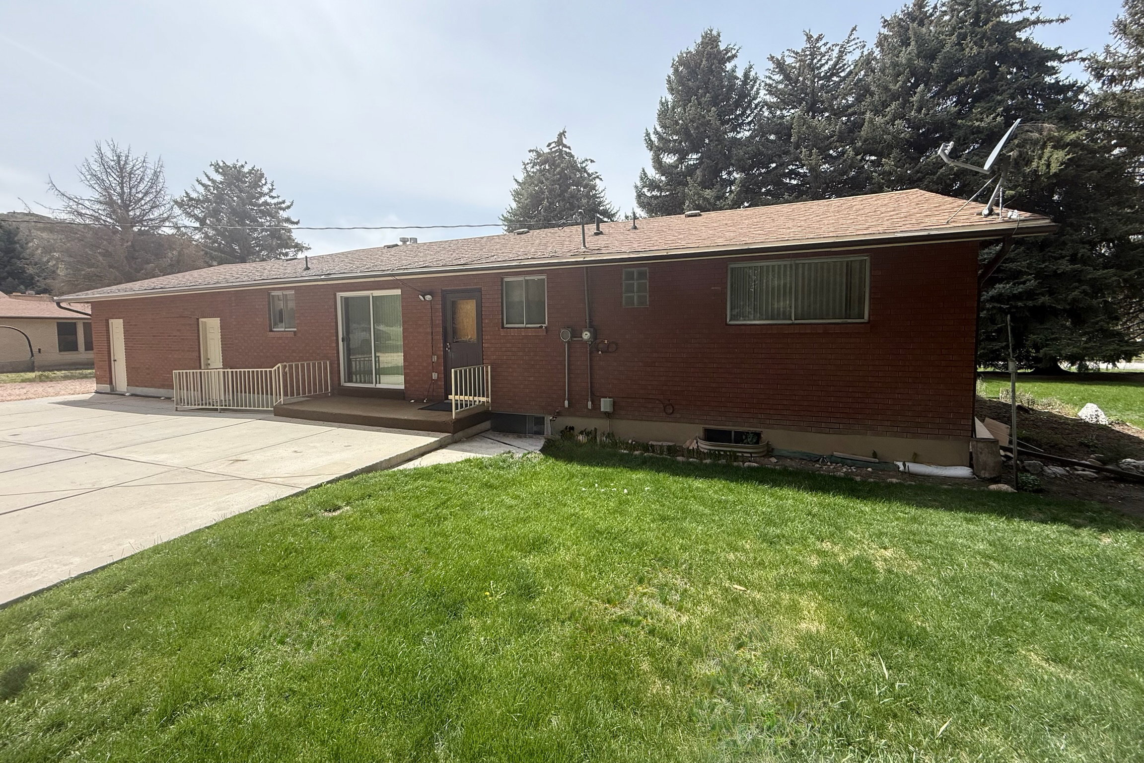 Rear view of house with a yard, brick siding, a deck, and roof with shingles