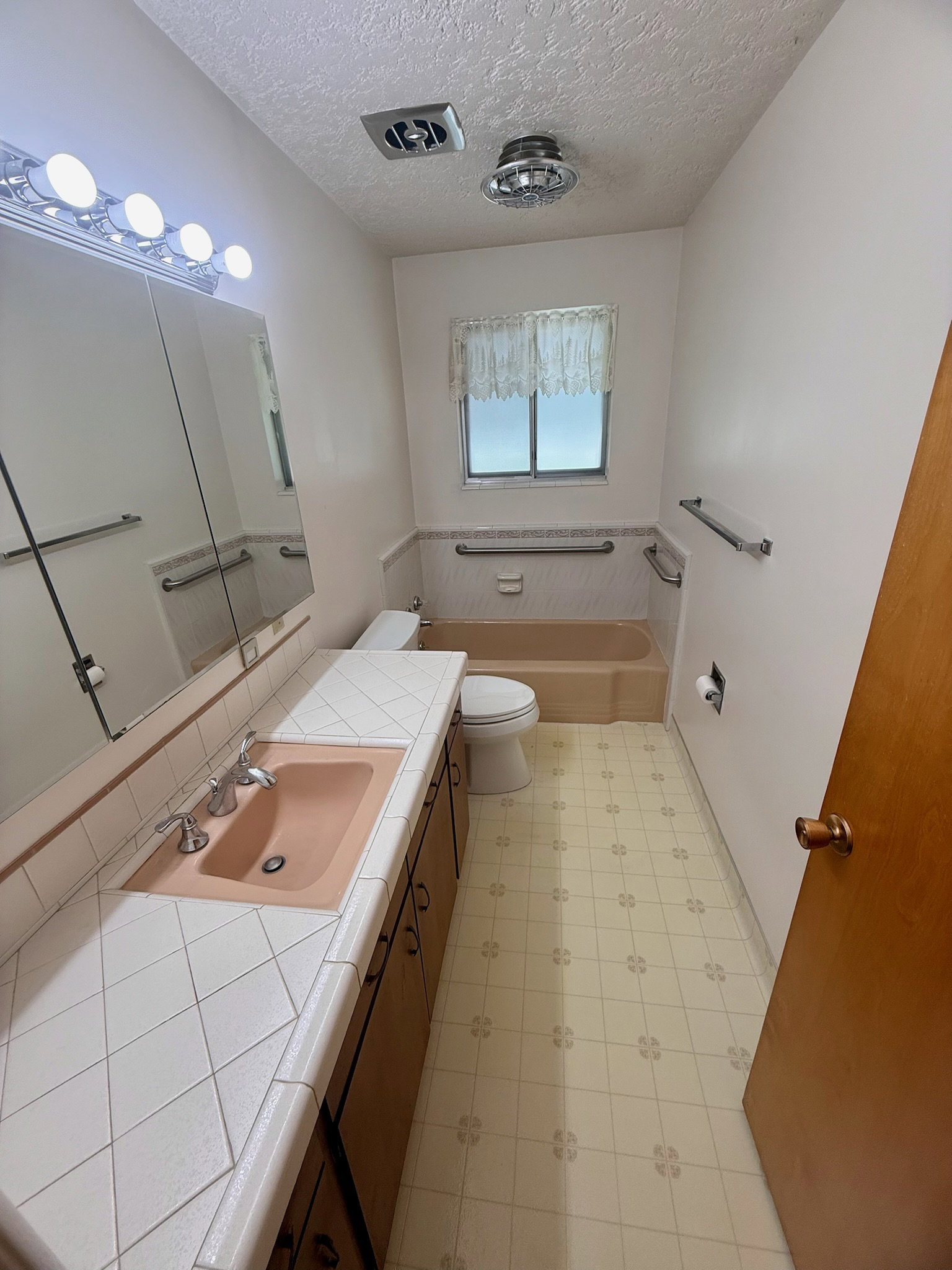 Full bathroom featuring light flooring, vanity, a bath, and a textured ceiling