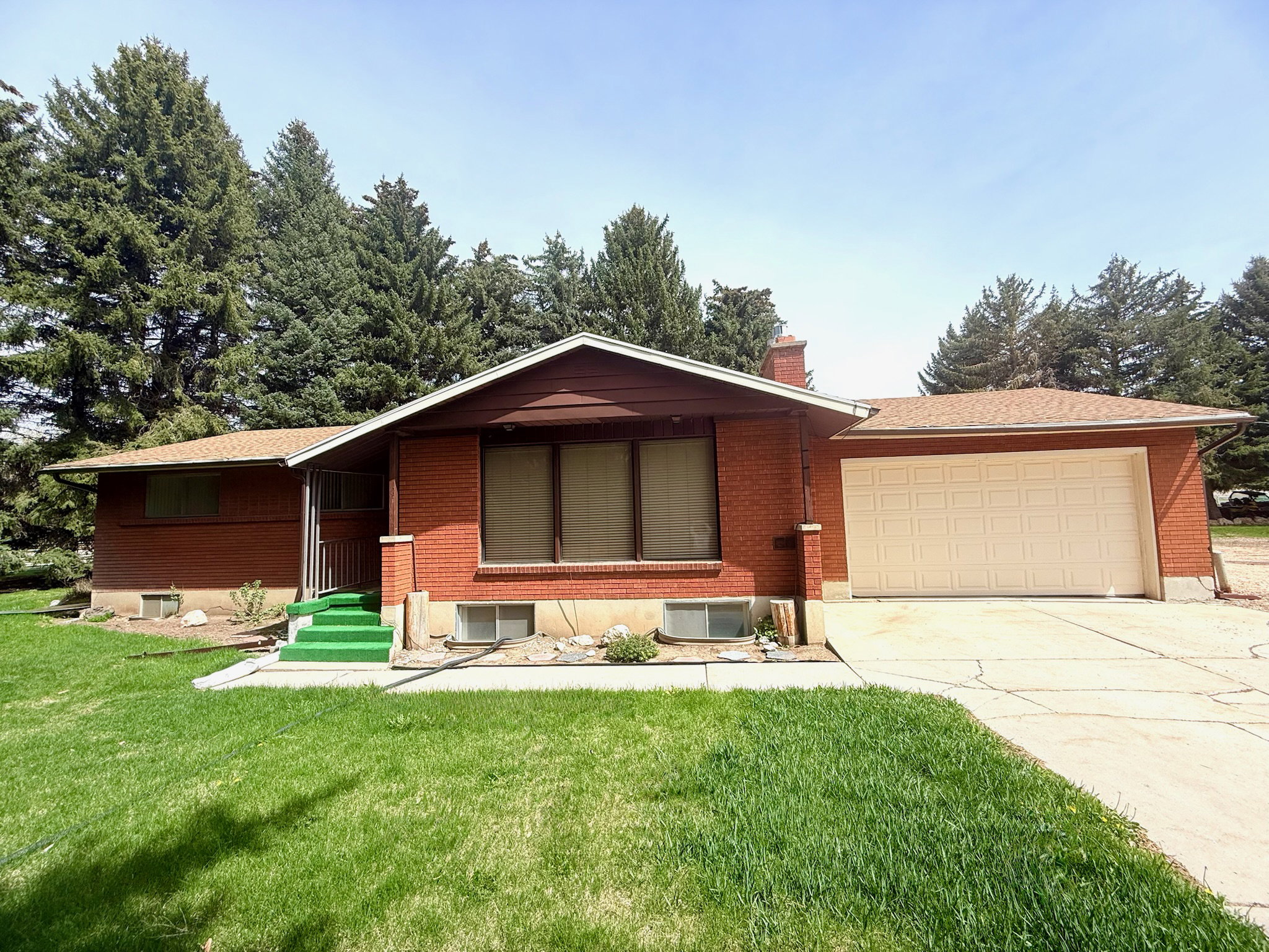 Ranch-style house with an attached garage, driveway, a front lawn, and a chimney