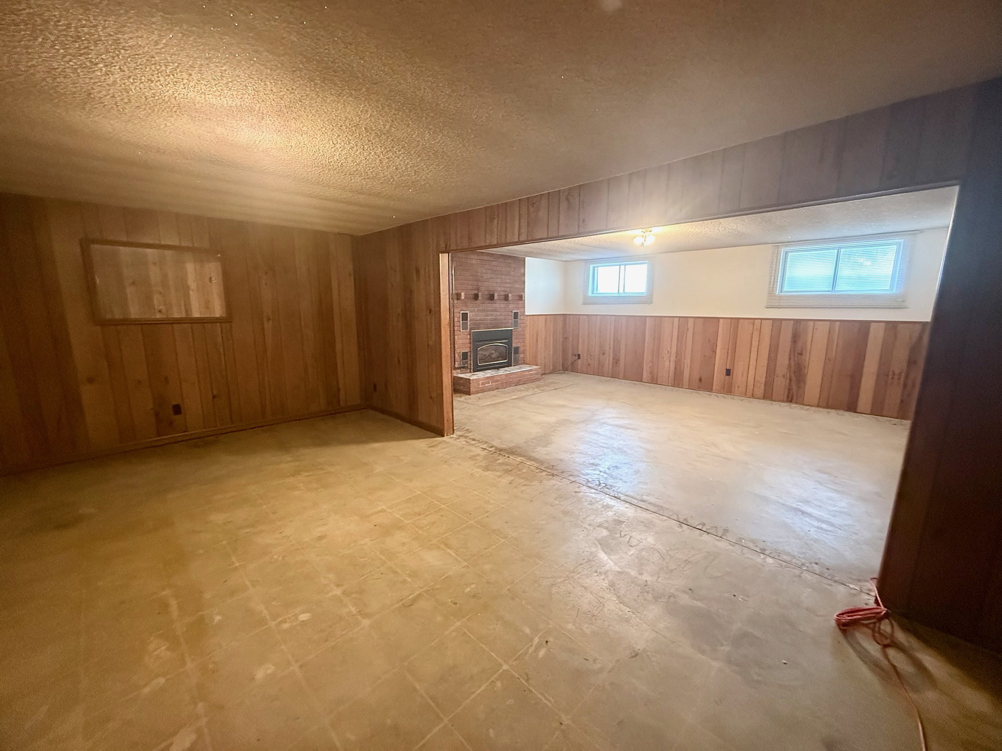 Basement with wooden walls, a wainscoted wall, a textured ceiling, tile patterned floors, and a fireplace