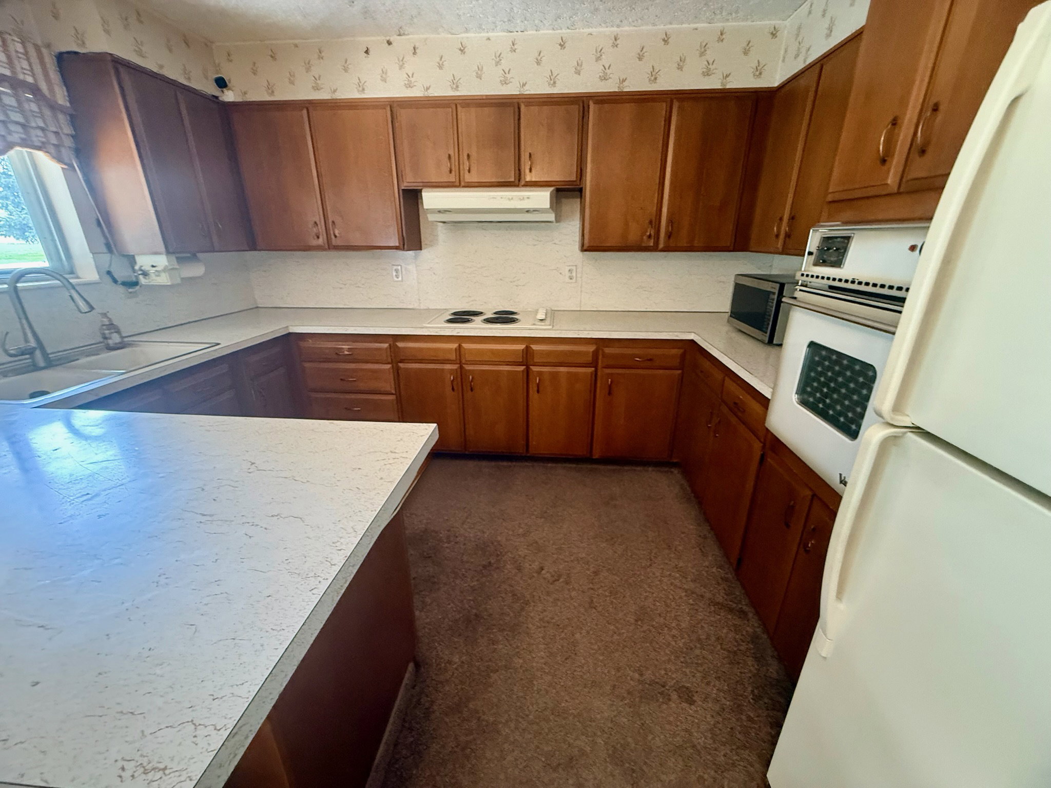 Kitchen with white appliances, wood finish cabinetry, light countertops, and decorative backsplash