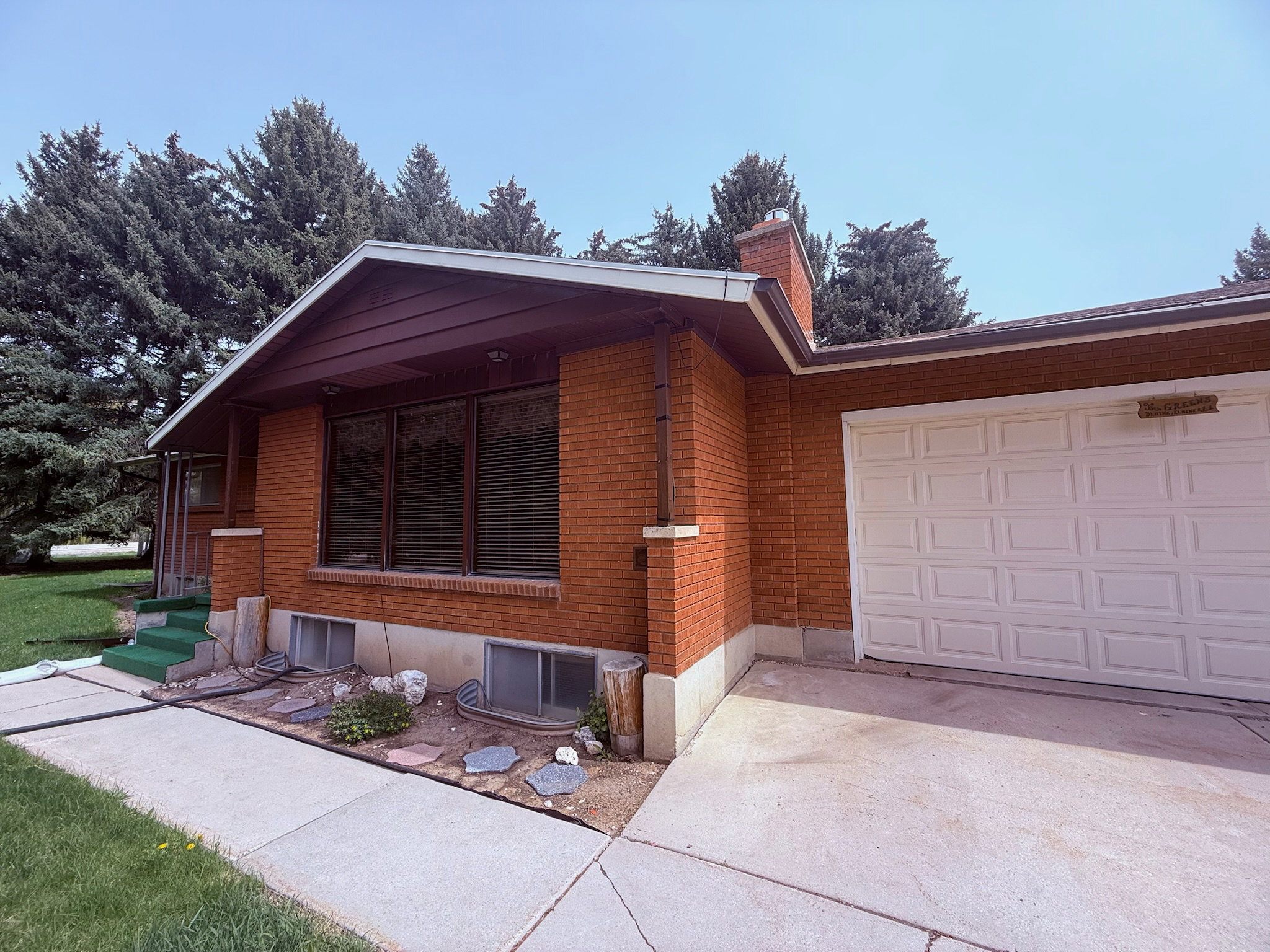 View of side of home featuring concrete driveway, an attached garage, brick siding, and a chimney