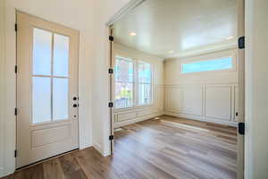 Doorway to outside with a decorative wall, wood finished floors, and recessed lighting