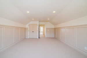 Bonus room featuring a decorative wall, light carpet, lofted ceiling, and recessed lighting