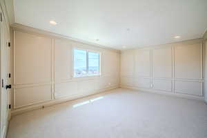 Empty room with a decorative wall, light carpet, and recessed lighting