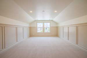 Additional living space with a decorative wall, light carpet, a textured ceiling, and recessed lighting