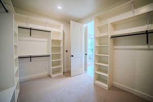 Walk in closet featuring light colored carpet
