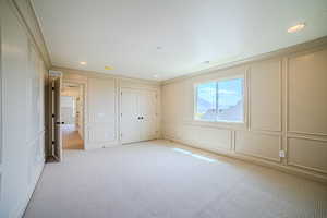 Unfurnished bedroom with a decorative wall, light colored carpet, and recessed lighting