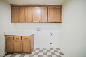 Laundry area featuring light floors, hookup for a washing machine, hookup for an electric dryer, and cabinet space
