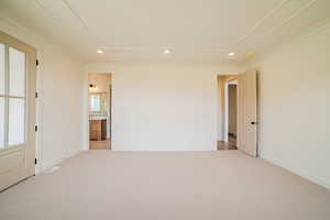 Unfurnished bedroom with light colored carpet, recessed lighting, and ensuite bathroom