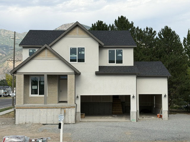Newly constructed residence featuring a light-toned exterior with dark shingle roofing