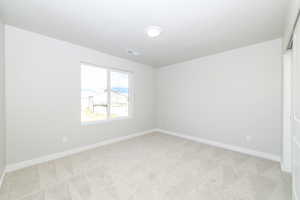 Spare room with light carpet and baseboards