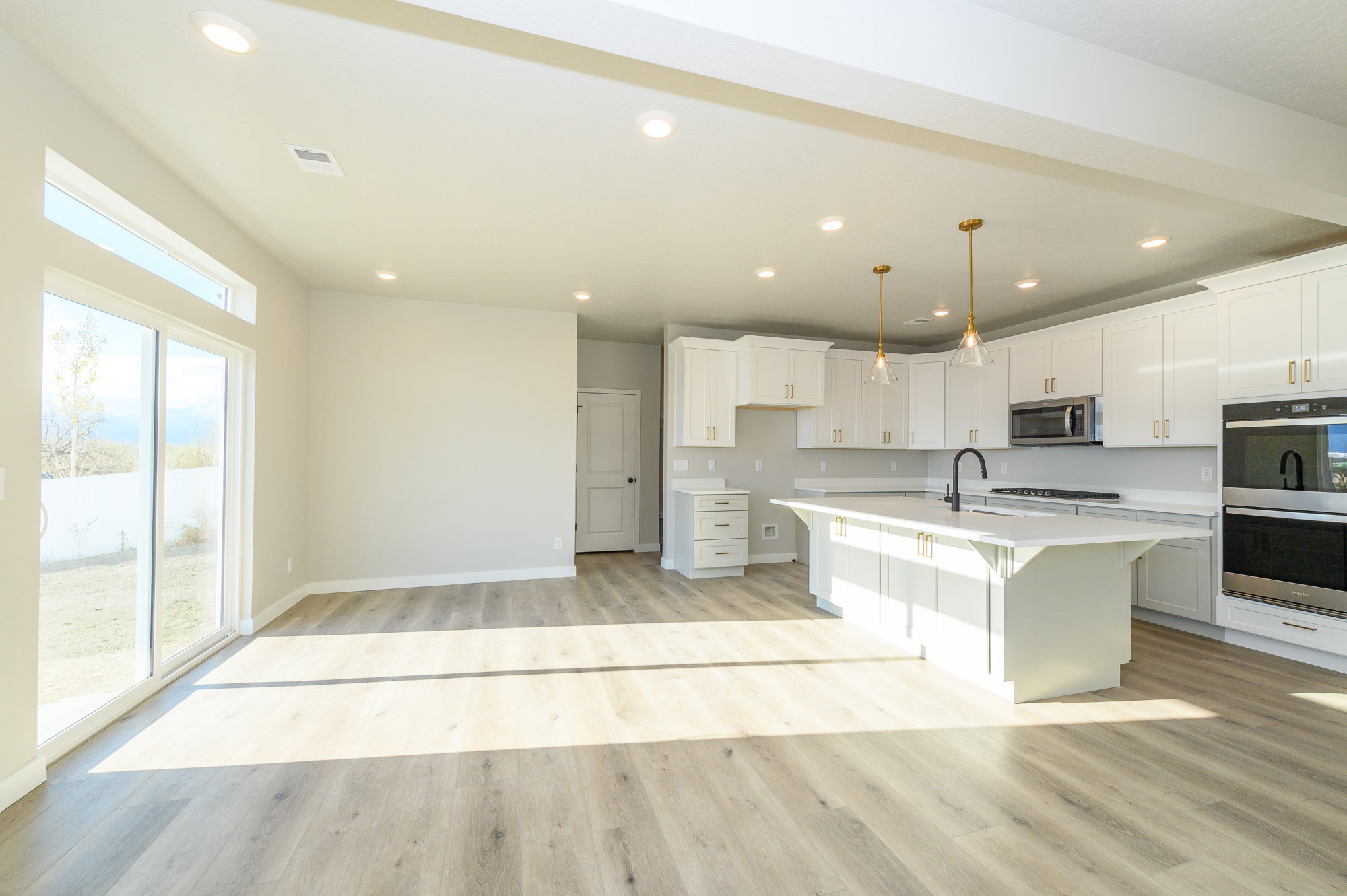 Kitchen featuring a kitchen bar, light wood finished floors, a center island with sink, and white cabinets