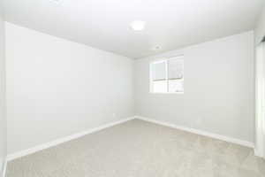 Spare room featuring light carpet and baseboards