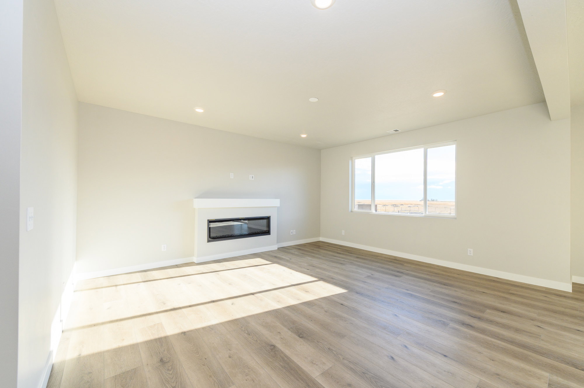 Unfurnished living room featuring light wood-style floors, recessed lighting, and a glass covered fireplace