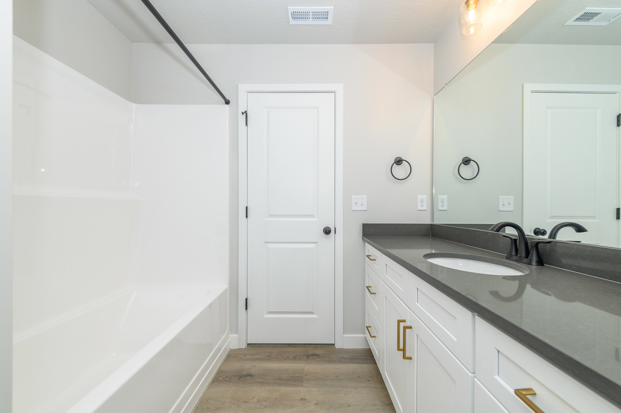 Bathroom featuring vanity, bathing tub / shower combination, and light wood-type flooring