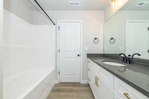 Bathroom featuring vanity, bathing tub / shower combination, and light wood-type flooring