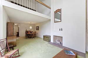Living area featuring a high ceiling and a fireplace with flush hearth