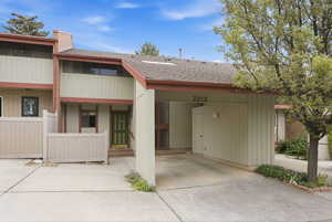 View of front of property with roof with shingles, driveway, and an attached carport