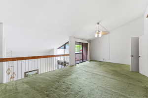 Carpeted empty room with vaulted ceiling and ceiling fan