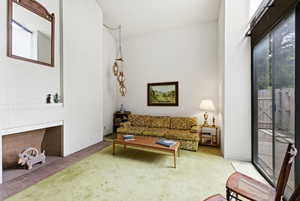 Living room with carpet, a high ceiling, and a fireplace