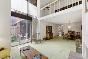 Living area featuring a high ceiling, light carpet, and hanging lights