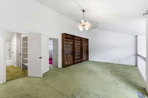 Unfurnished bedroom featuring vaulted ceiling, carpet floors, a ceiling fan, and connected bathroom