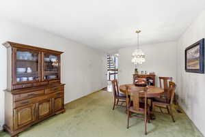 Dining space featuring light colored carpet and hanging lights