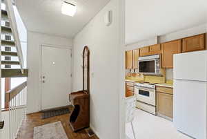 Kitchen with white appliances, light countertops, and a textured ceiling