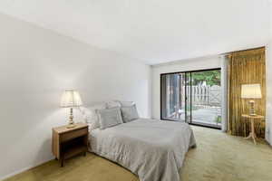 Carpeted bedroom featuring a textured ceiling and access to exterior