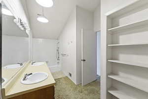 Full bathroom with vaulted ceiling, double vanity, bathing tub / shower combination, and a closet