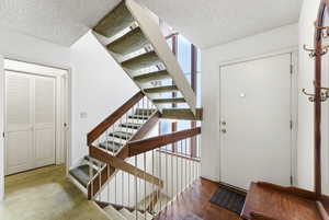 Staircase featuring a textured ceiling, plenty of natural light, and parquet flooring