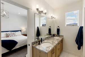 Full bathroom with double vanity, connected bathroom, and a chandelier