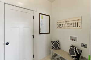 Laundry room with hookup for a washing machine, electric dryer hookup, and light tile patterned floors